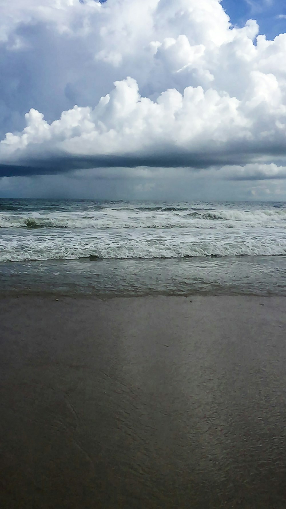 ocean waves crashing on shore under white clouds and blue sky during daytime