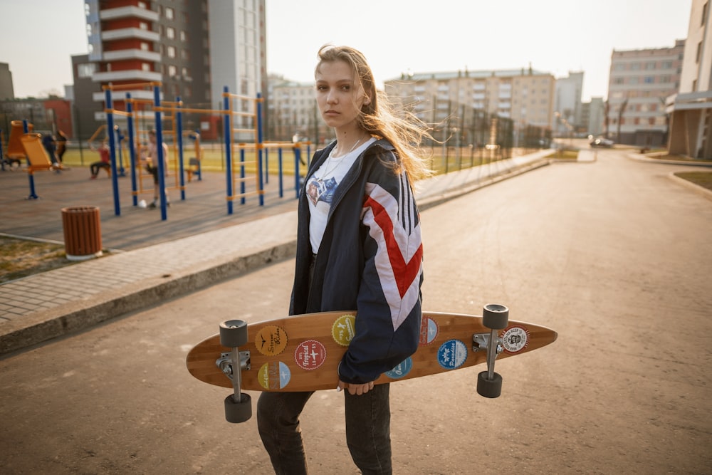 woman in blue jacket and black pants holding skateboard