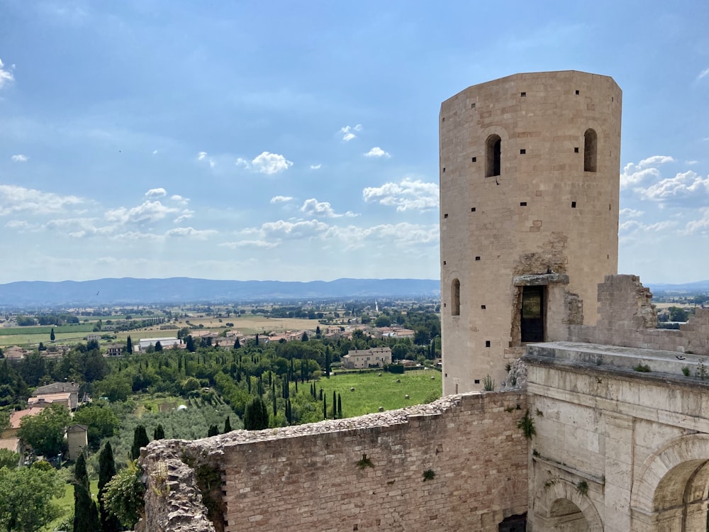 edificio in cemento marrone vicino agli alberi verdi sotto il cielo blu durante il giorno