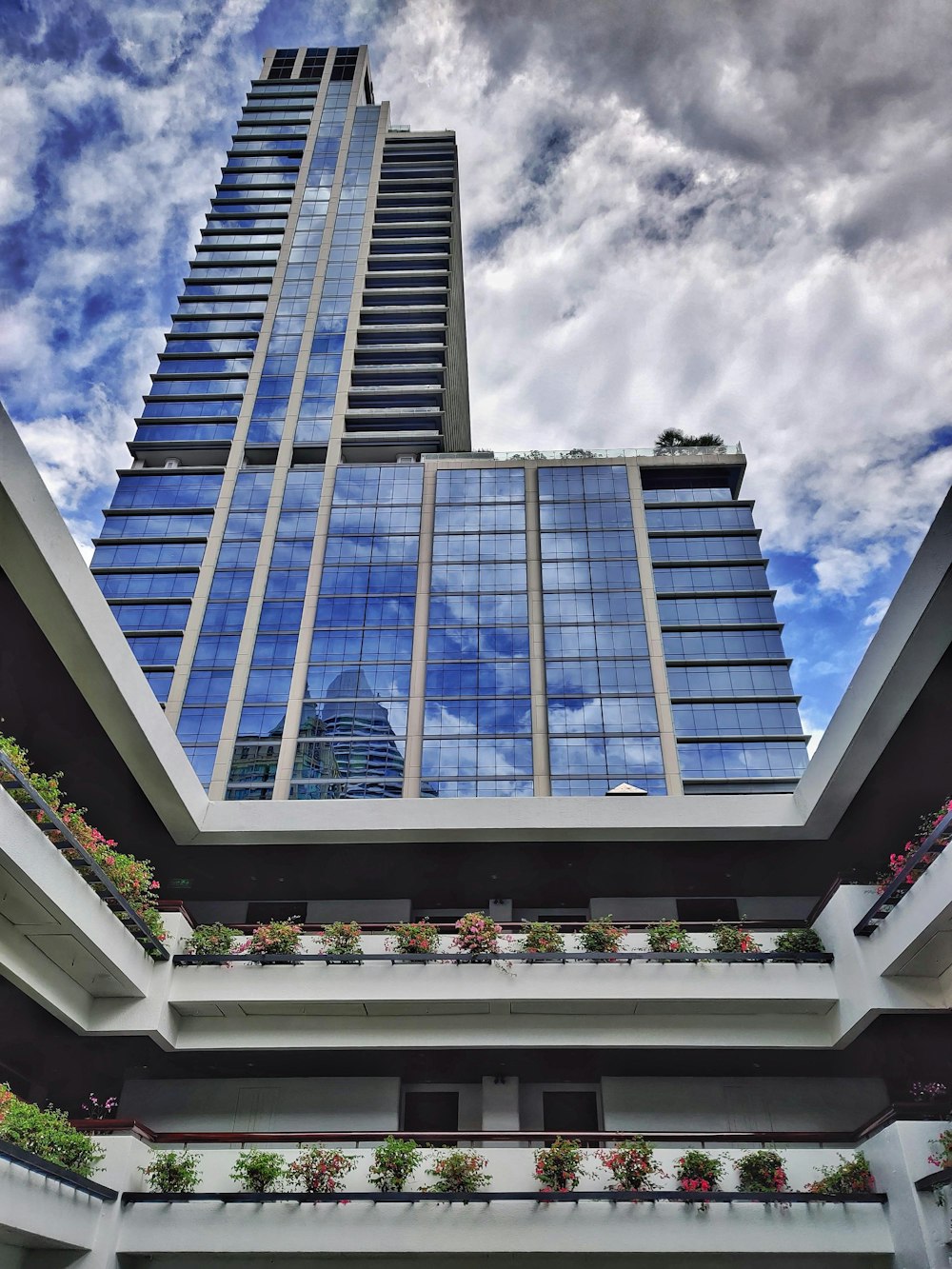 blue and white glass walled building under white clouds and blue sky during daytime