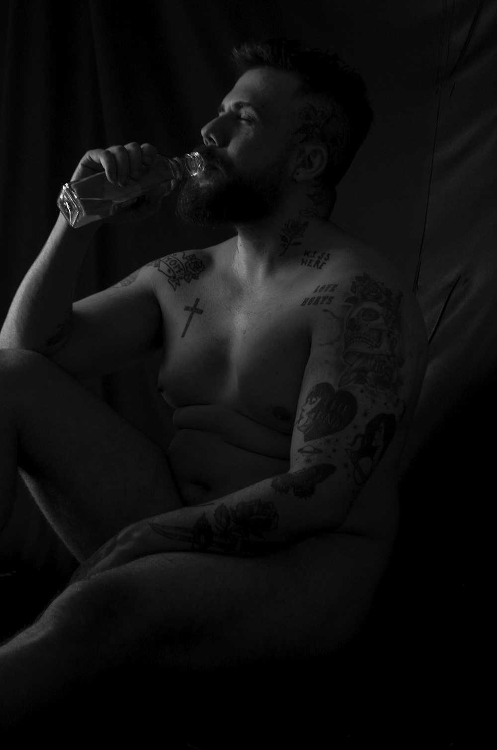topless man drinking water from bottle
