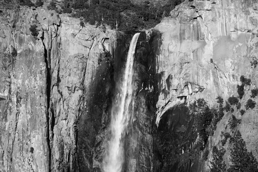 grayscale photo of waterfalls in rocky mountain
