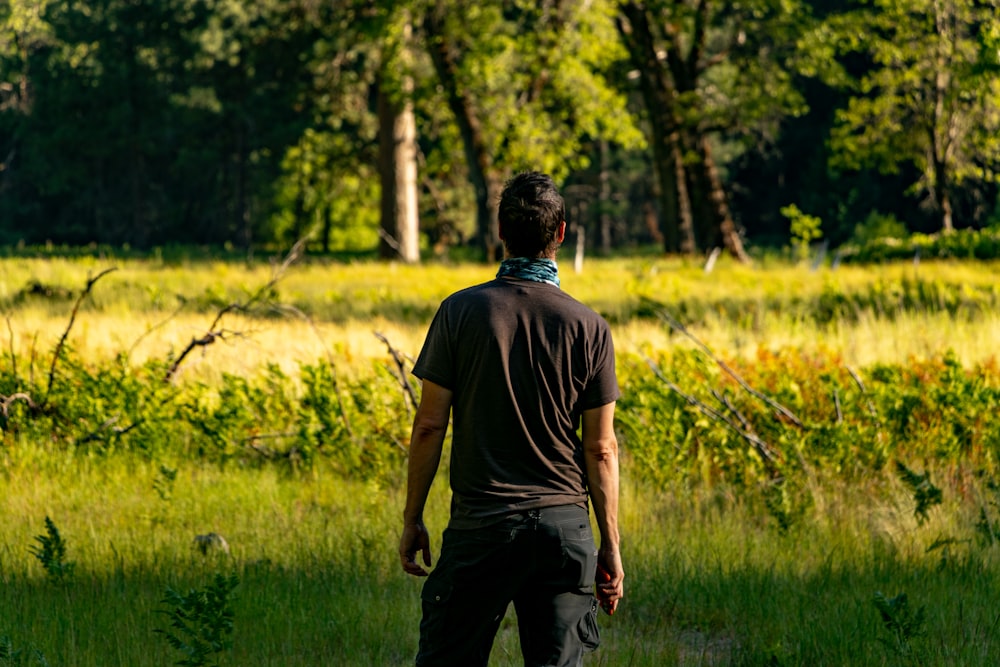 man in black t-shirt walking on green grass field during daytime