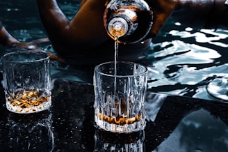 person pouring water on clear drinking glass