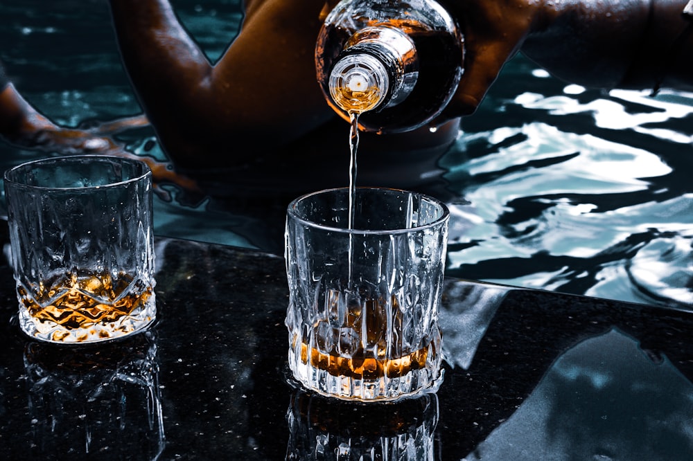 person pouring water on clear drinking glass