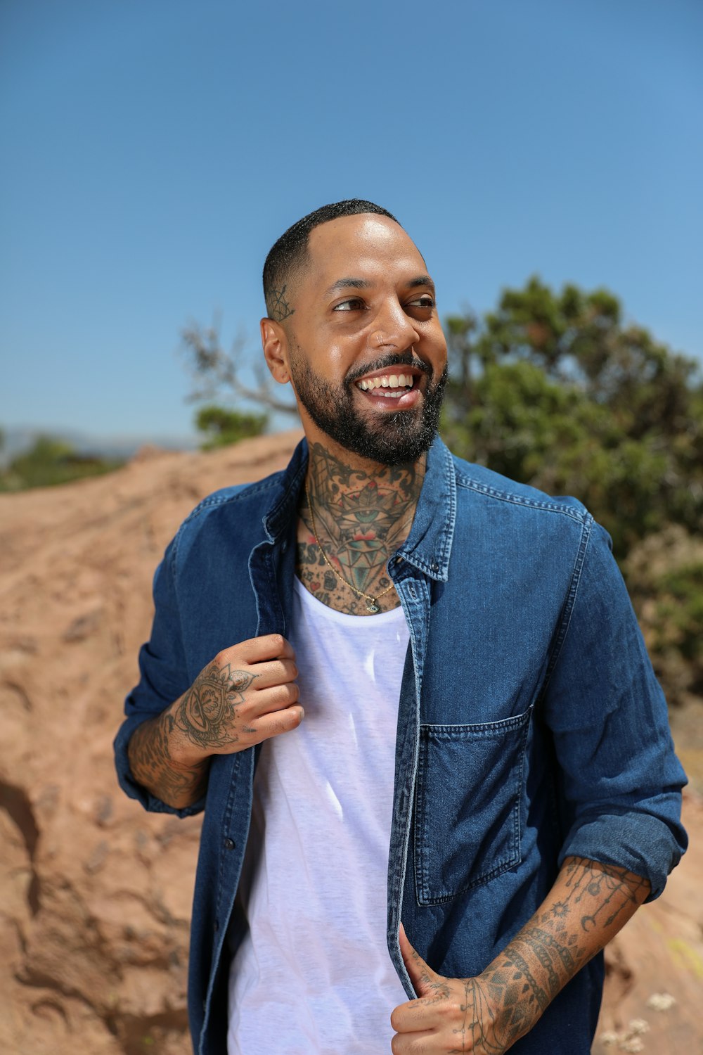 man in blue denim jacket standing on brown sand during daytime