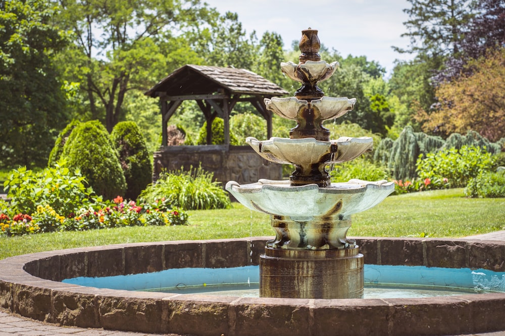 brown concrete fountain near green trees during daytime