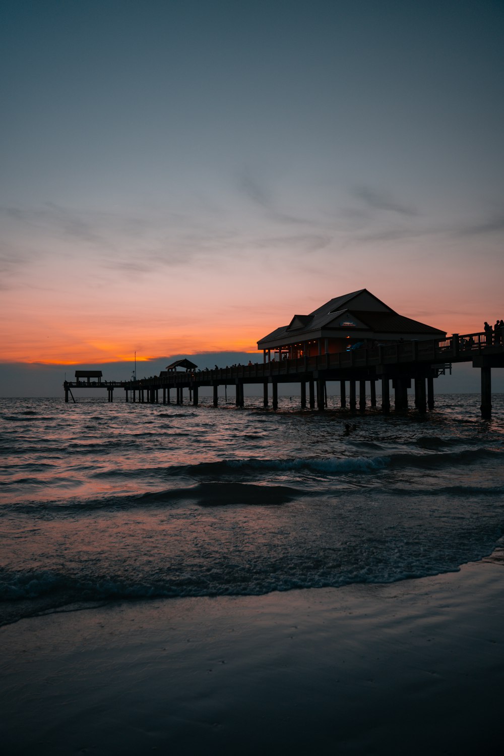 muelle de madera marrón en el mar durante la puesta del sol