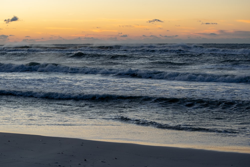 ocean waves crashing on shore during sunset