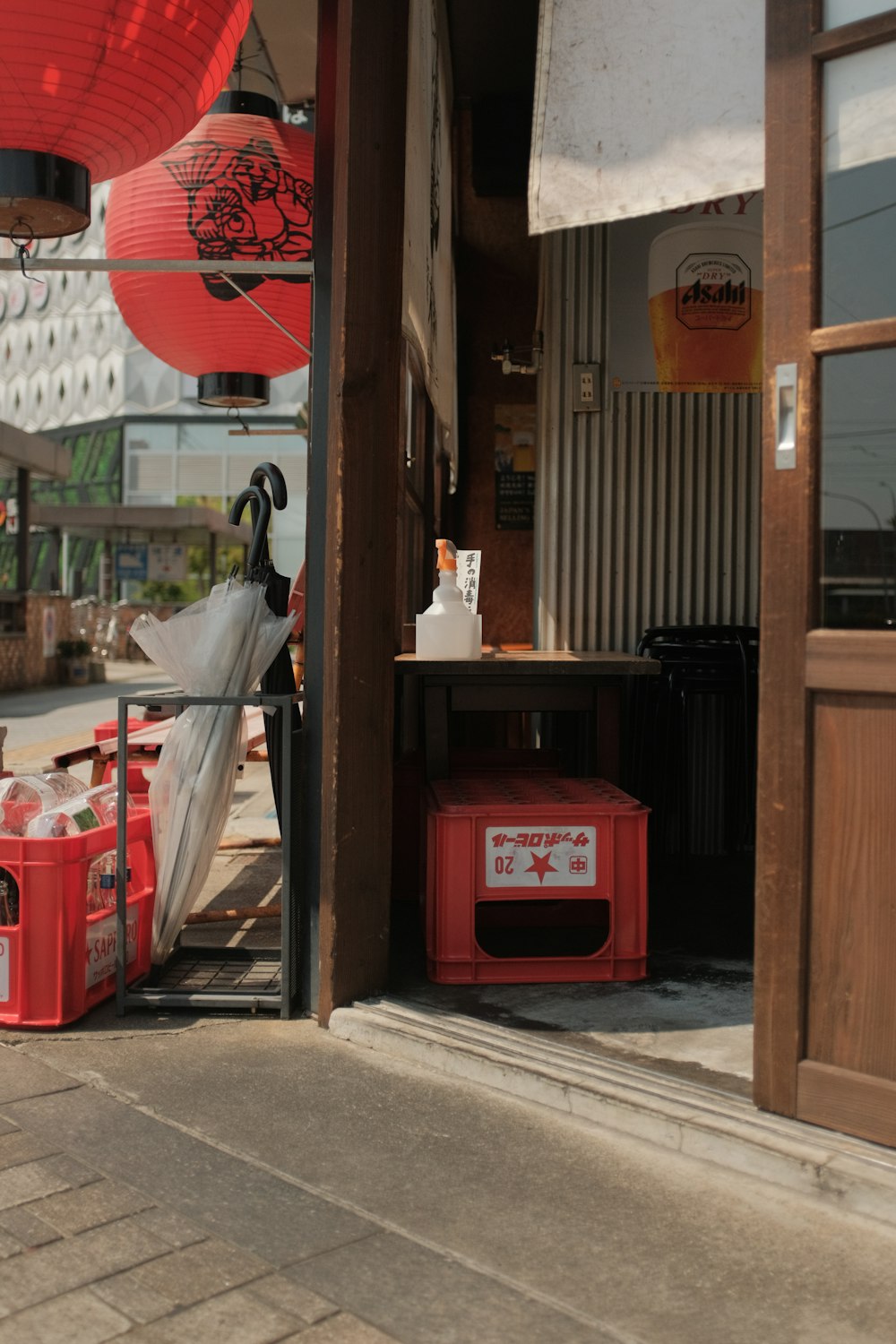 red plastic trash bin beside brown wooden door