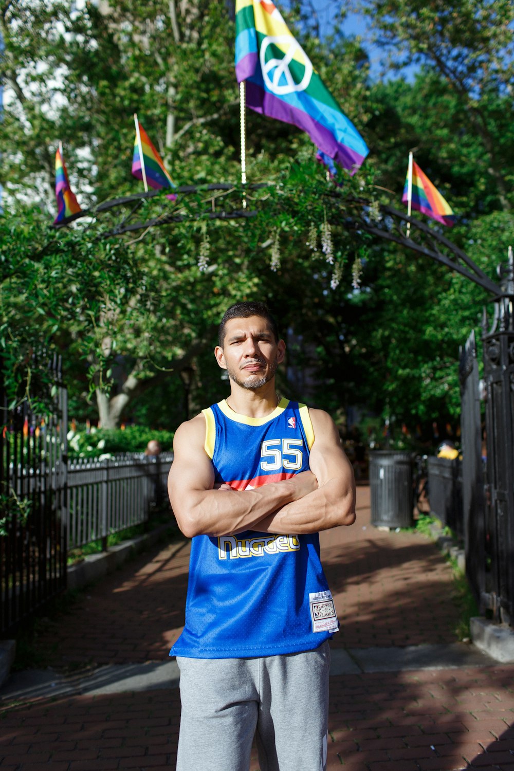 man in blue tank top holding purple and yellow umbrella