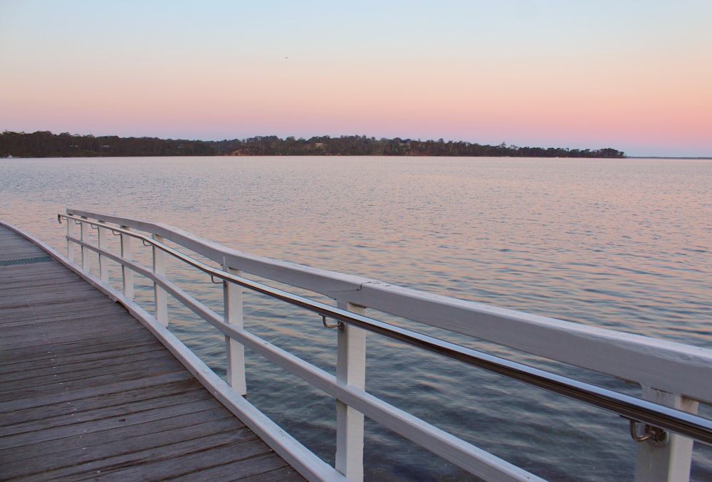 a long wooden dock next to a large body of water