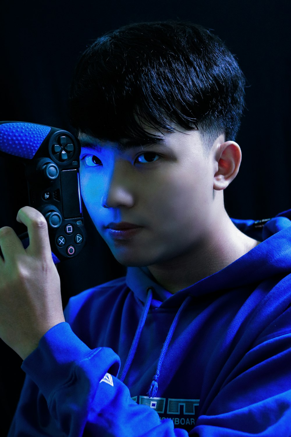 Junge im blauen Langarmhemd mit schwarzem Gamecontroller