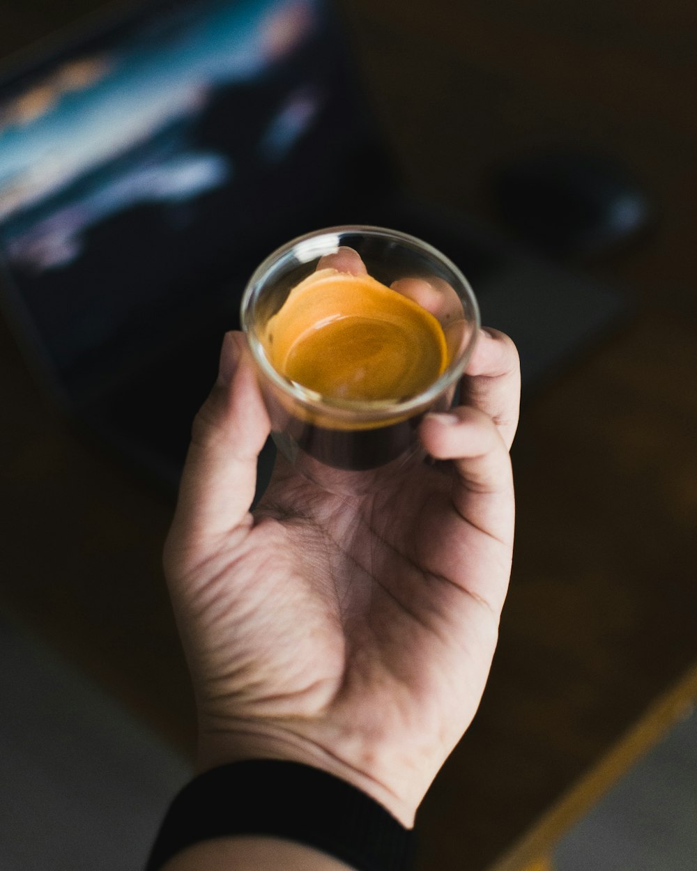 persona sosteniendo un vaso transparente con líquido amarillo