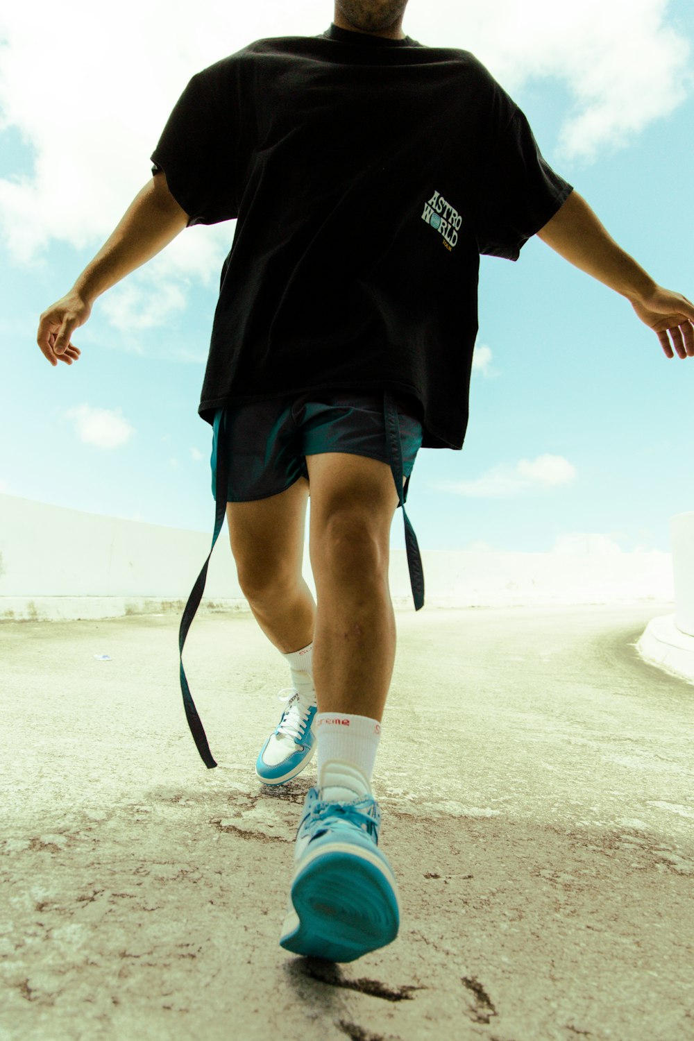 man in black crew neck t-shirt and blue shorts standing on white sand during daytime