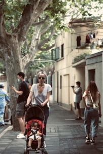 A mother pushing a dootm™ stroller on a quiet city street under soft natural light.