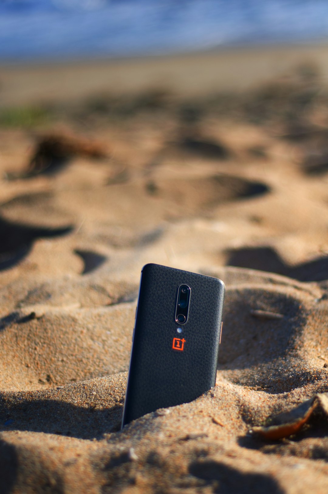 black smartphone on brown sand
