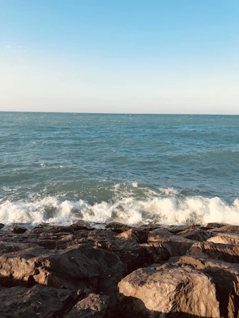 Waves crashing against the rocky Atlantic coastline with a bright, clear sky overhead.