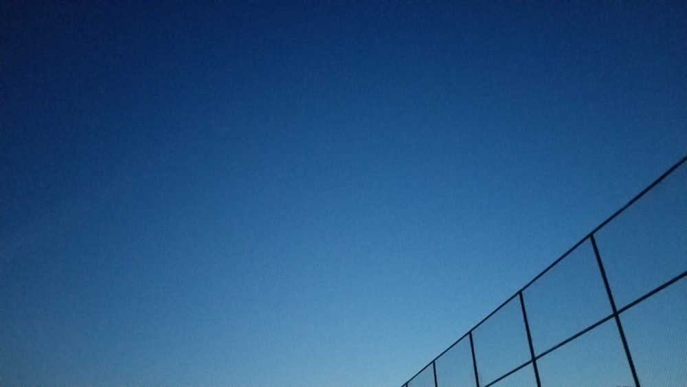 blue sky over black metal fence