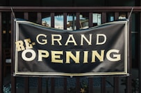 a black and gold sign that says grand opening