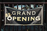 a black and gold sign that says grand opening