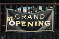 a black and gold sign that says grand opening