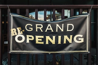 a black and gold sign that says grand opening