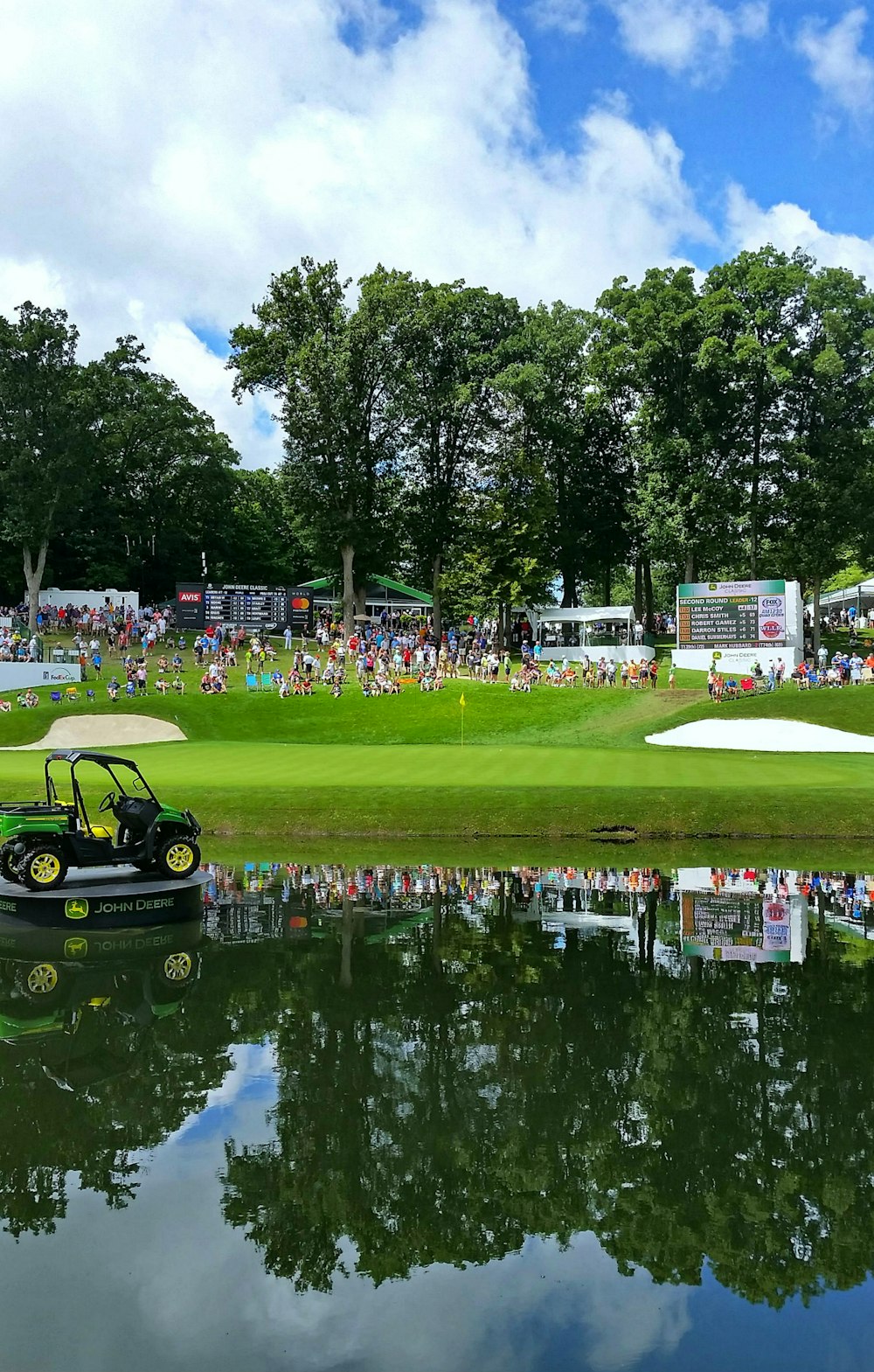 green golf cart on green grass field near body of water during daytime