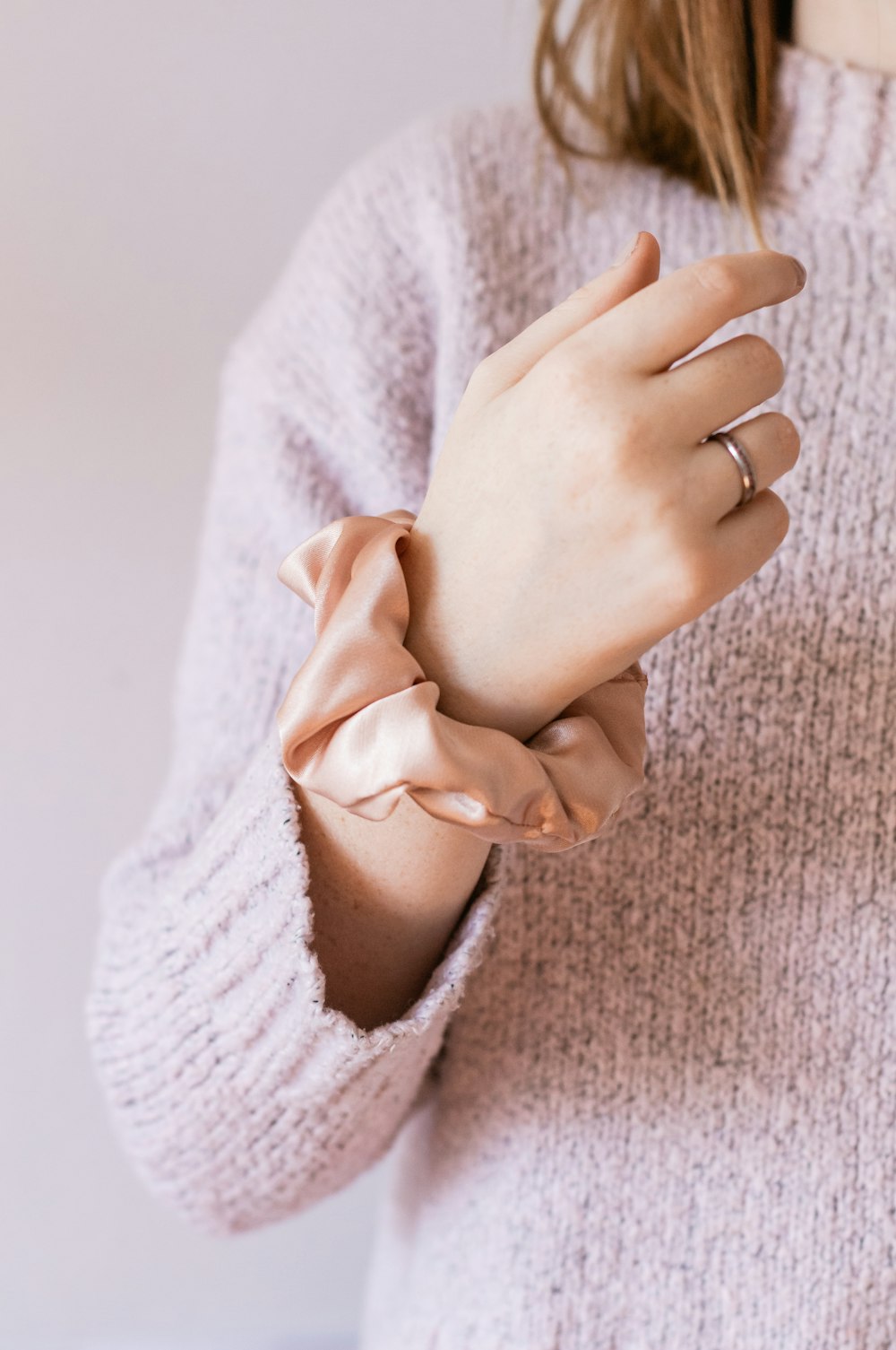 woman in white knit sweater holding her hand