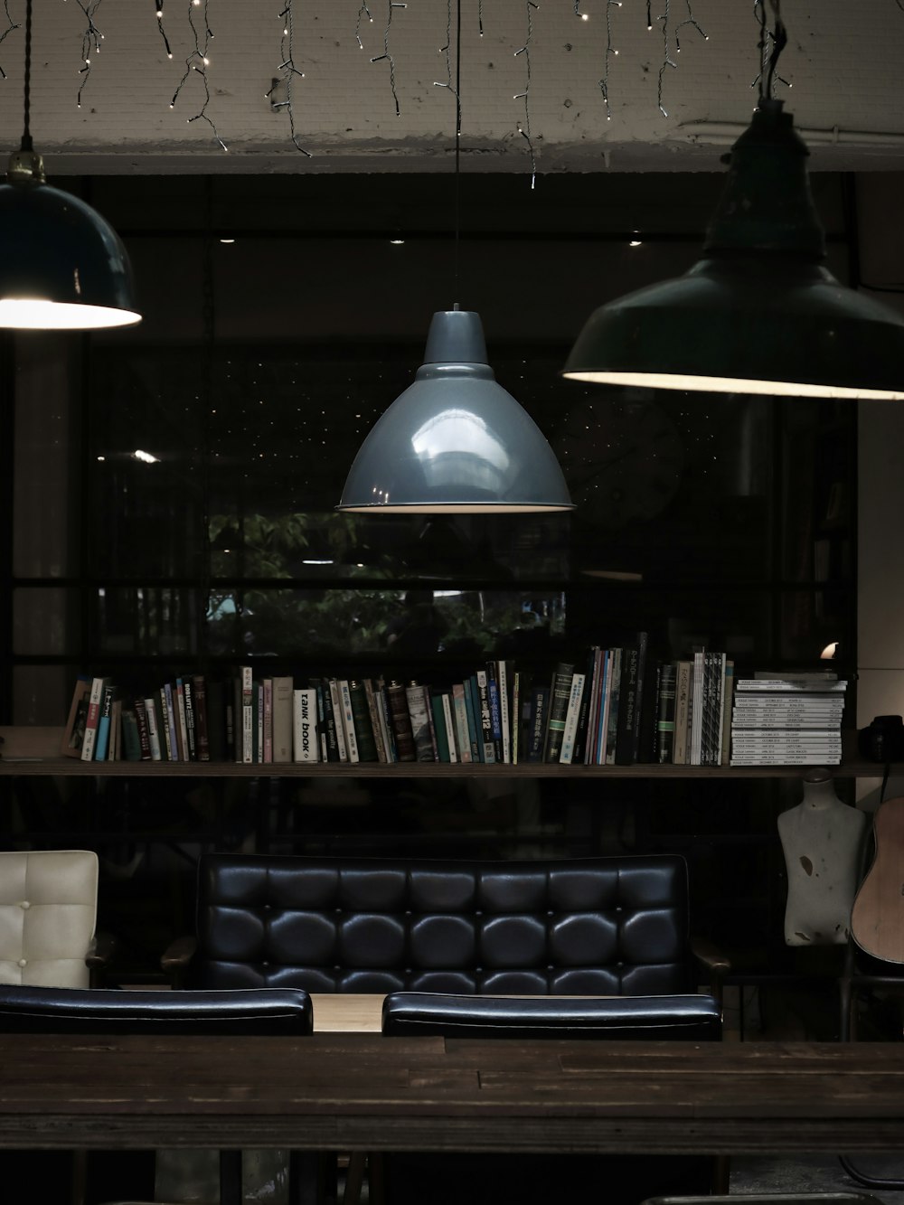 black wooden book shelf with books and pendant lamps