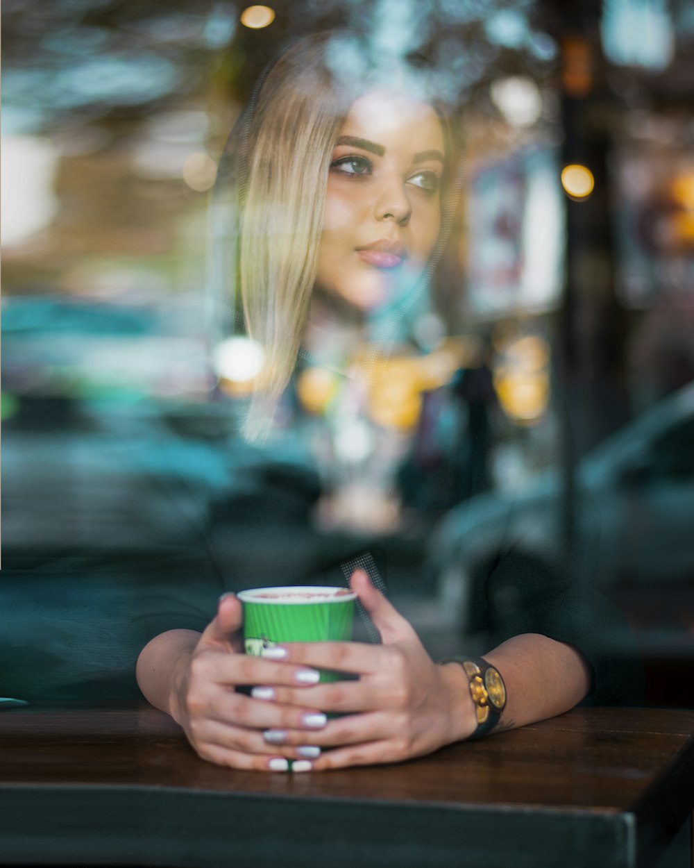 woman in green and white polka dot shirt holding green and white cup