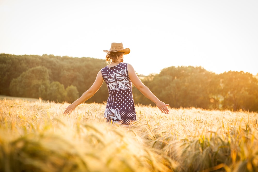 woman in black and white floral dress standing on brown grass field during daytime