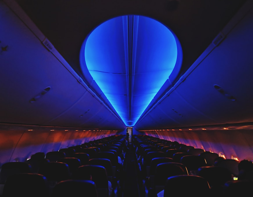 Traveler comfortably resting on a plane seat using an ergonomic neck pillow with soft ambient cabin lighting