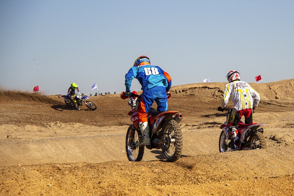 people riding motocross dirt bikes on brown sand during daytime