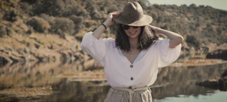 woman in white long sleeve shirt and brown and black striped skirt standing near body of with with with with