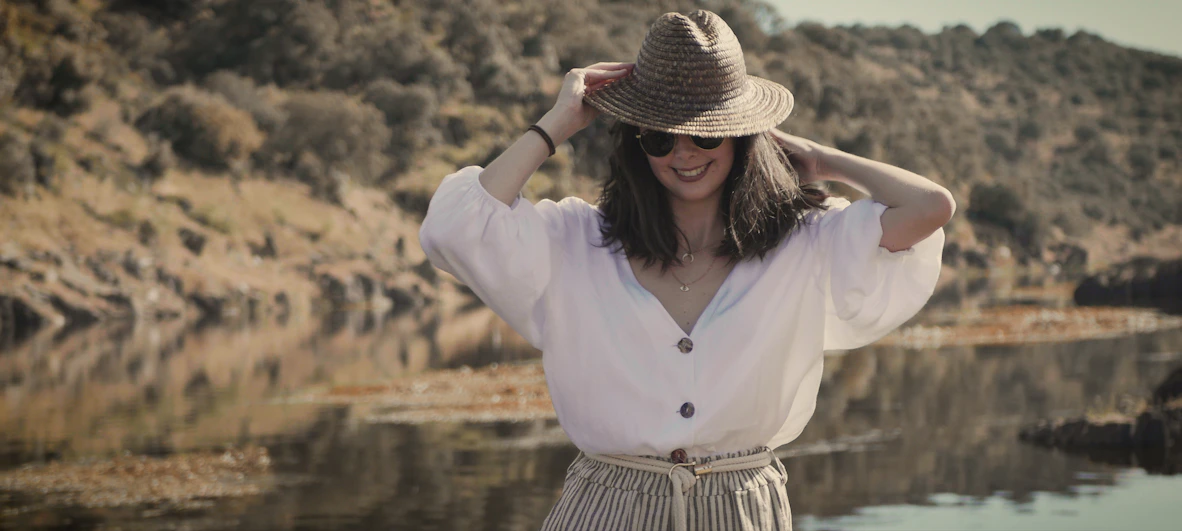 woman in white long sleeve shirt and brown and black striped skirt standing near body of with with with with