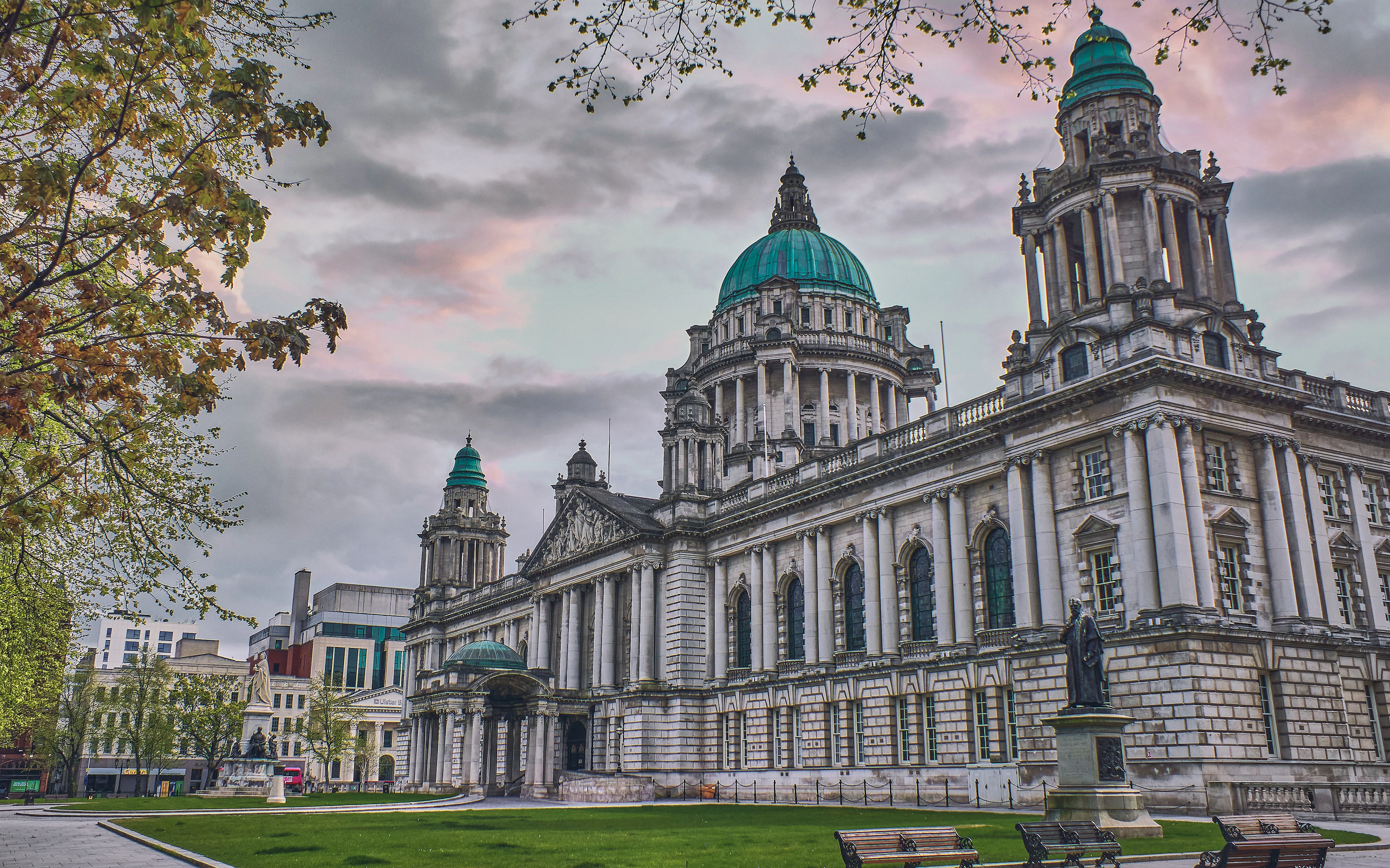 The grand Portland-stone facade and green copper domes of Belfast City Hall under a moody sky.