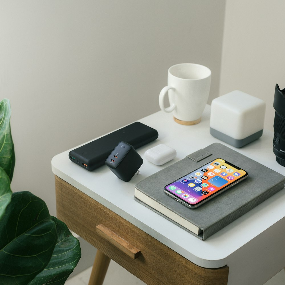 black iphone 4 beside white ceramic mug on white table