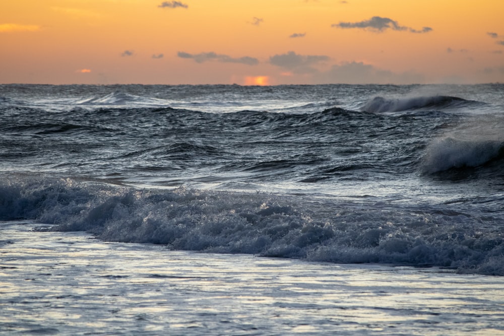 ocean waves under orange sky during sunset