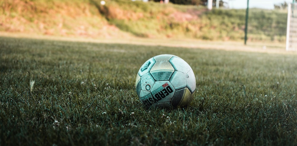 white and black soccer ball on green grass field during daytime