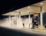 man in yellow jacket standing near gas pump