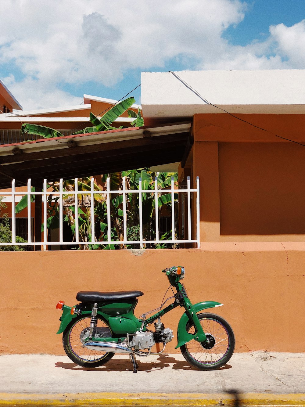 green and black motorcycle parked beside brown concrete building during daytime