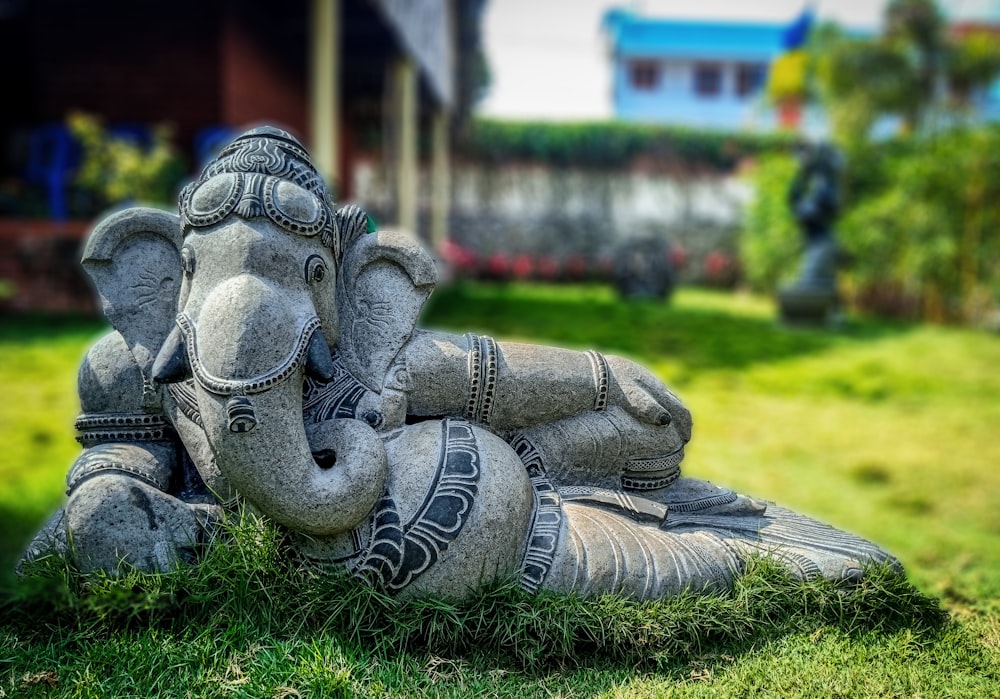 estatueta cinzenta do elefante na grama verde durante o dia
