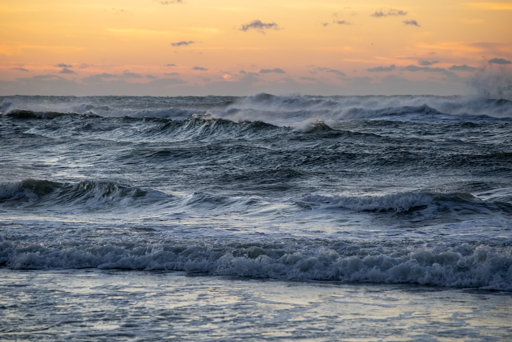 ocean waves crashing on shore during sunset