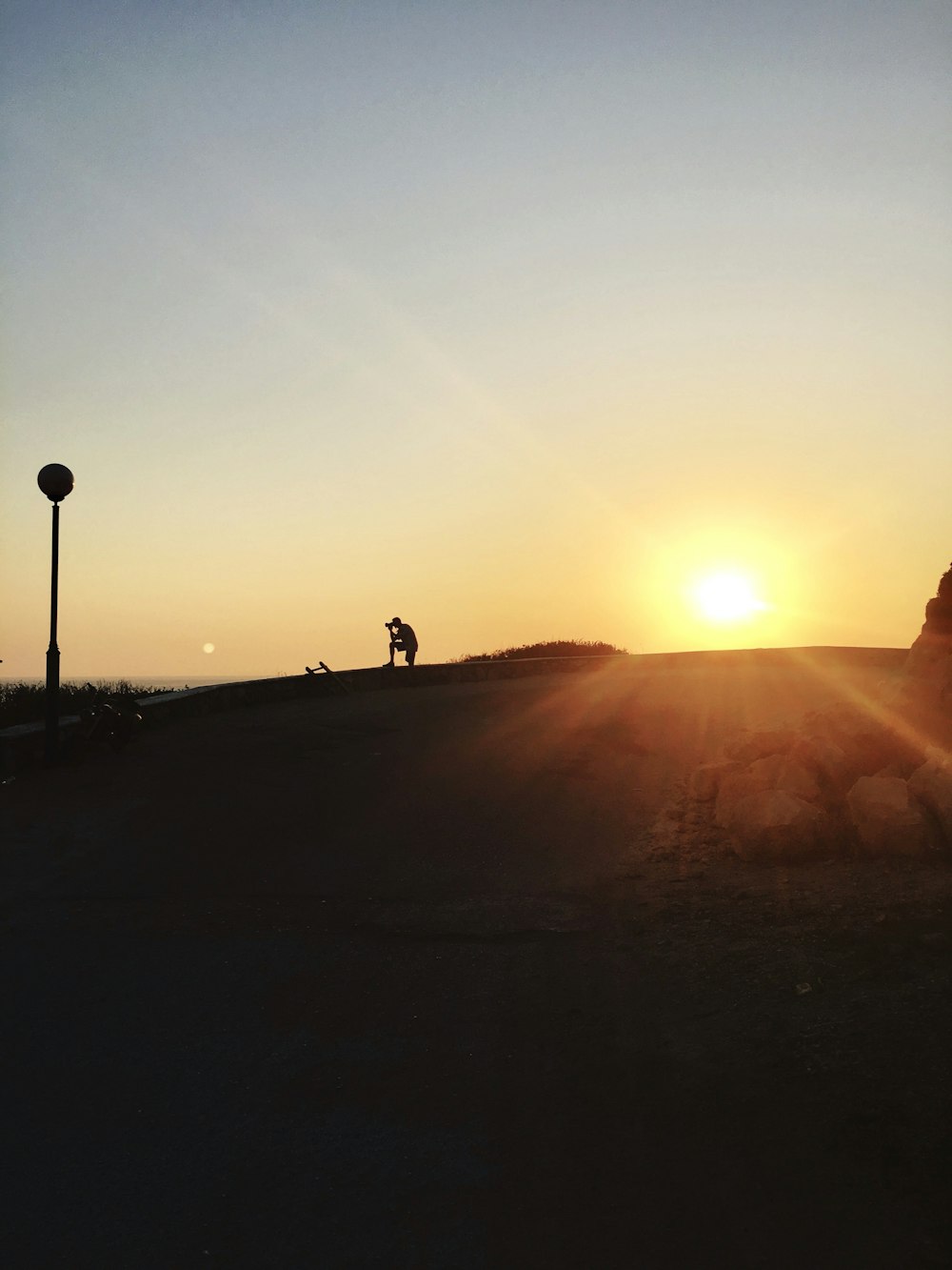 silhouette of person riding motorcycle on road during sunset