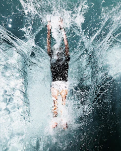 man in black shorts and white shirt in water