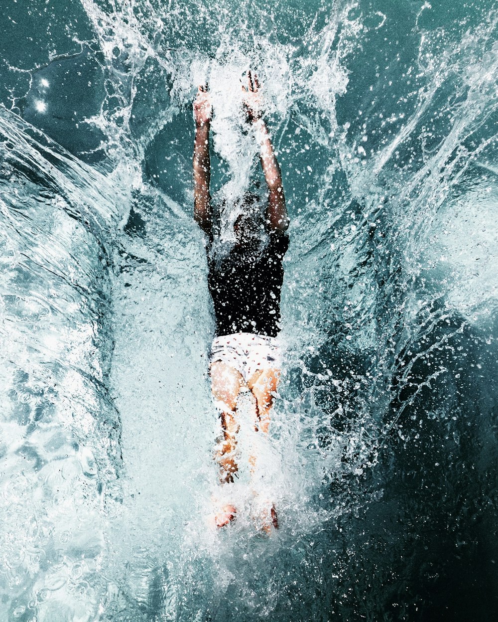 Mann in schwarzen Shorts und weißem Hemd im Wasser