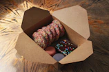 An open bake box showing an assortment of cookies and pastries wrapped in parchment paper.