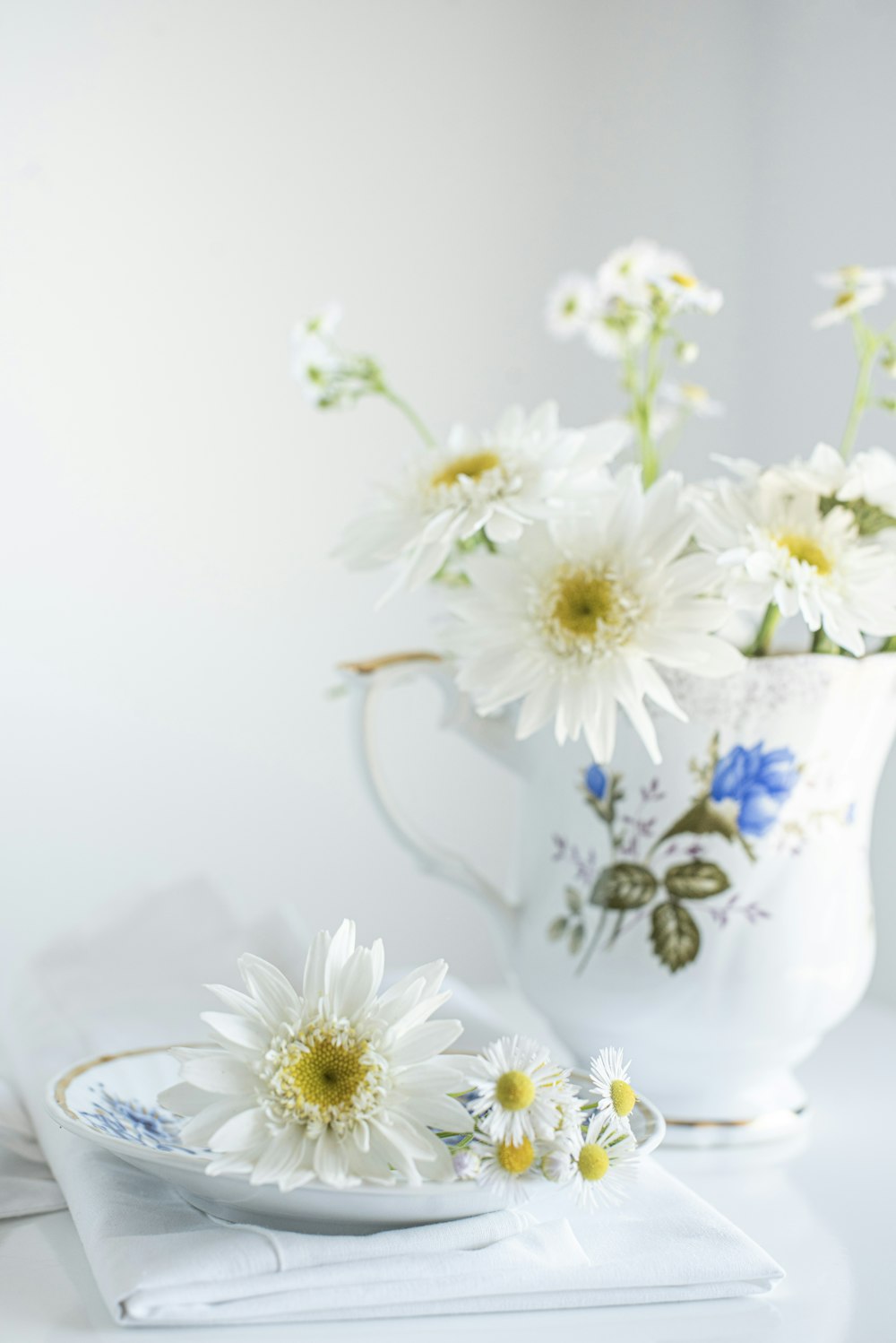 white and yellow flowers in white ceramic vase