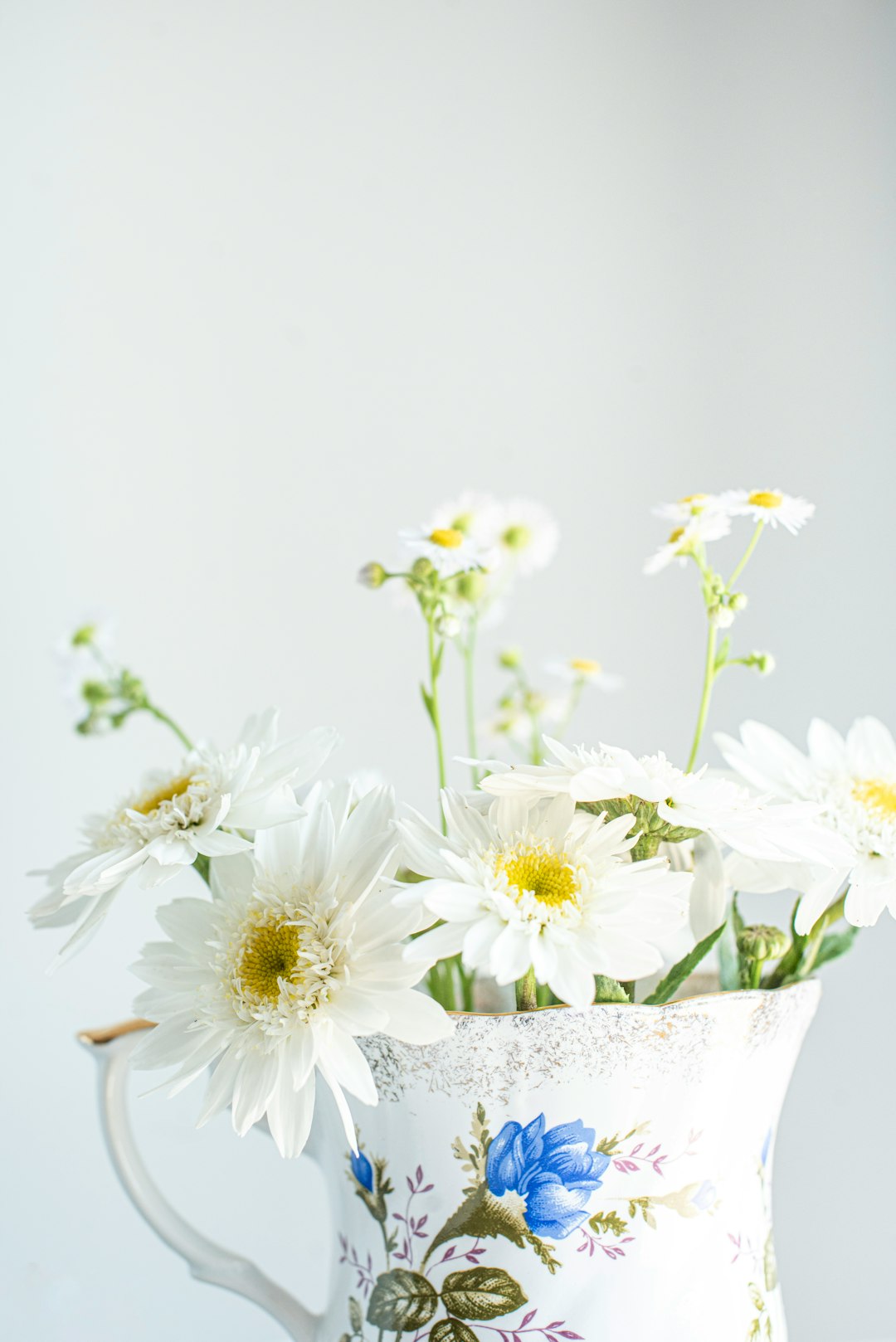 white and yellow flowers in white ceramic vase